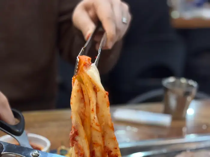 집게로 김치 잎을 들어 올리는 모습