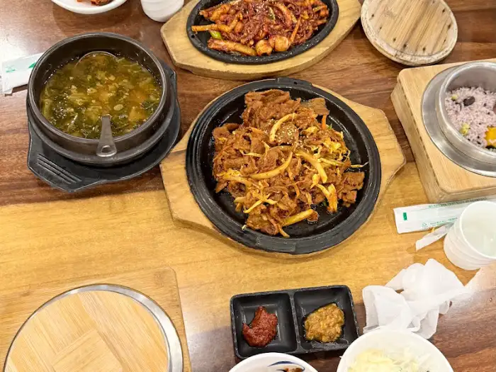 정갈하게 담긴 제육볶음과 솥밥, 찌개가 보인다.