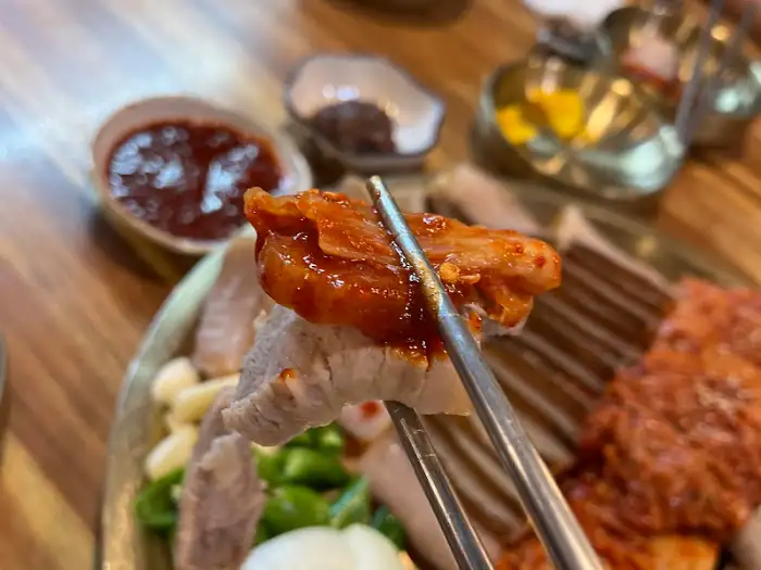 젓가락으로 집어든 묵은지와 삼겹살