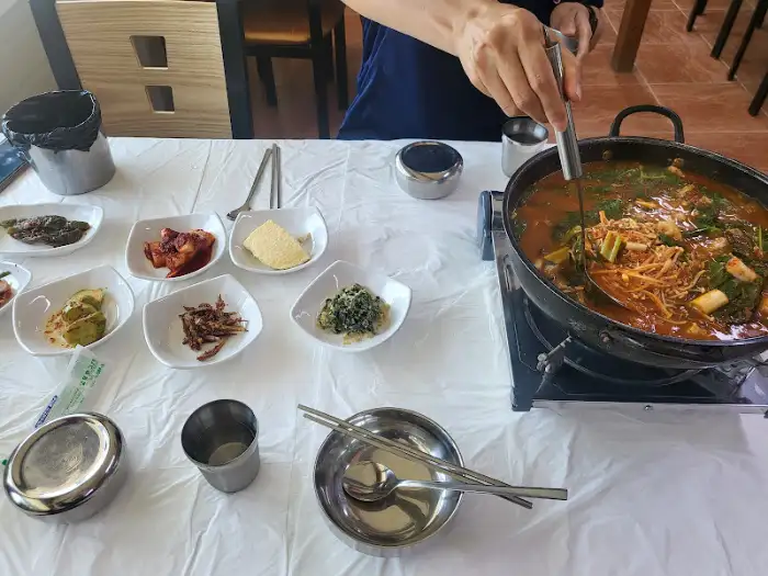 테이블에 세팅된 메인 요리와 밑반찬, 그리고 국자를 이용해 매운탕을 뜨는 모습