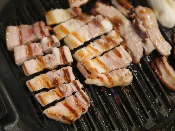 숯불 위에서 맛있게 익어가고 있는 두툼한 삼겹살