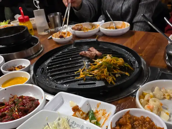 식사 중인 테이블의 모습, 고기와 반찬들이 조화롭게 놓여있다.