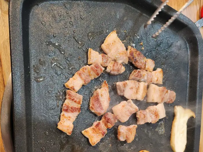 불판 위에서 맛있게 익어가고 있는 삼겹살 조각들