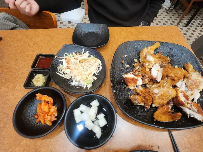 치킨, 샐러드, 김치, 치킨무 등 다양한 반찬이 놓인 테이블