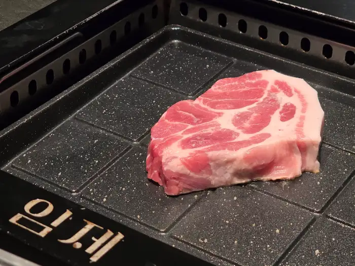 팬 위에 놓인 두툼한 삼겹살 덩어리.