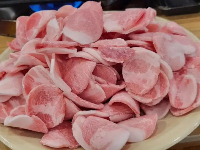 접시에 수북이 담긴 얇게 썬 돼지고기