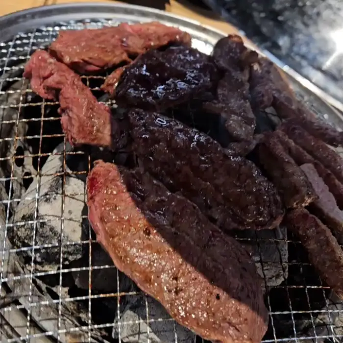 숯불 위에서 구워지고 있는 두툼한 소고기 조각들