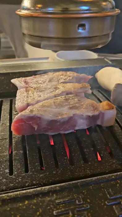 숯불 위에서 육즙을 머금고 있는 두툼한 돼지고기