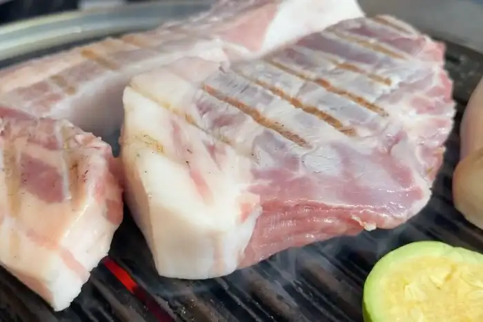 불판 위에서 구워지고 있는 두툼한 삼겹살