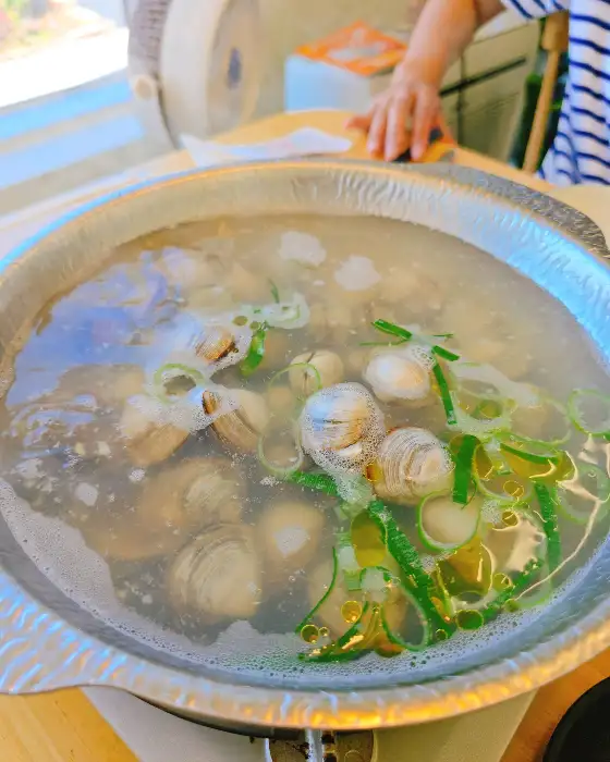 조개와 파가 끓고 있는 도브레만돌 샤브샤브 냄비