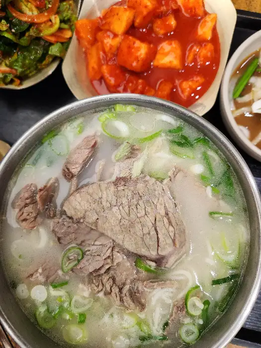 그릇에 담긴 설렁탕 위에 큼직한 고기 조각들과 파가 듬뿍 올려져 있는 모습