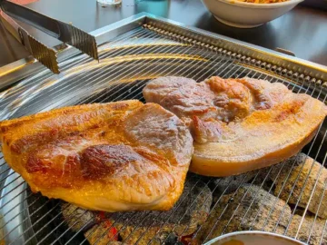 제주흑돈 본점에서 숯불 위에 구워지고 있는 두툼한 흑돼지 오겹살