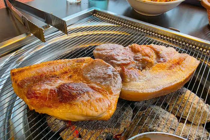 제주흑돈 본점에서 숯불 위에 구워지고 있는 두툼한 흑돼지 오겹살