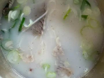 뽀얗게 우러난 깊고 진한 설렁탕 국물 위로 큼직한 고기와 파가 듬뿍 올려진 모습
