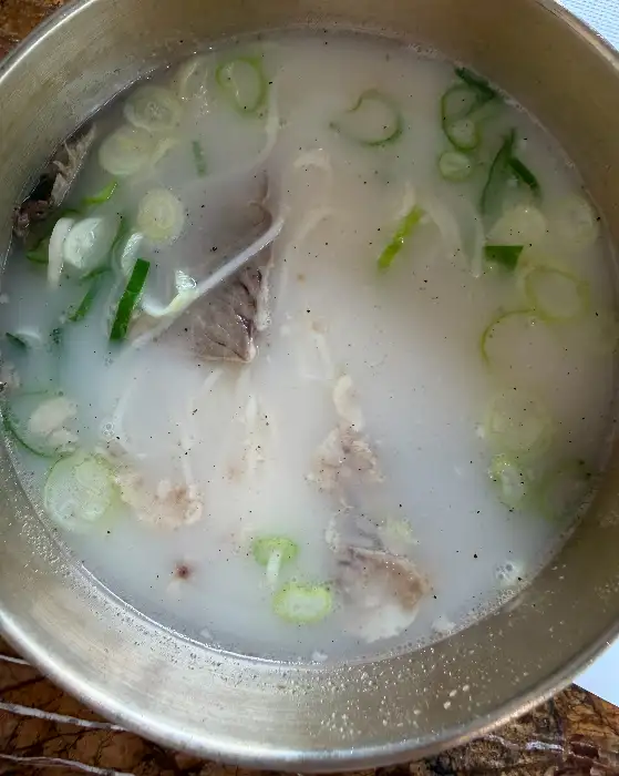 뽀얗게 우러난 깊고 진한 설렁탕 국물 위로 큼직한 고기와 파가 듬뿍 올려진 모습