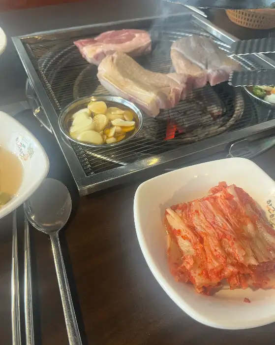 테이블 위에 준비된 숯불 구이와 김치, 그리고 멜젓 소스