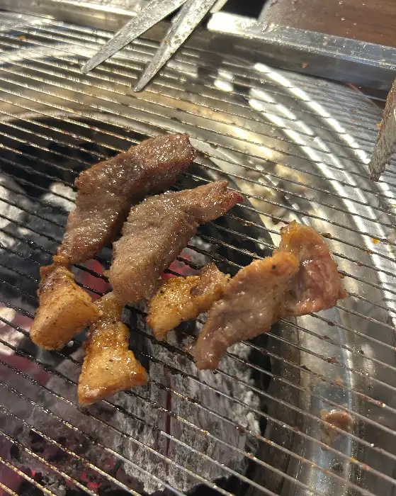 제주흑돈 본점의 숯불 위에서 구워지고 있는 흑돼지 삼겹살과 갈비살 조각들