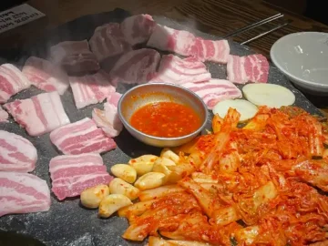 석암생소금구이 진주하대점 돌판에 구워지는 생고기와 김치, 마늘