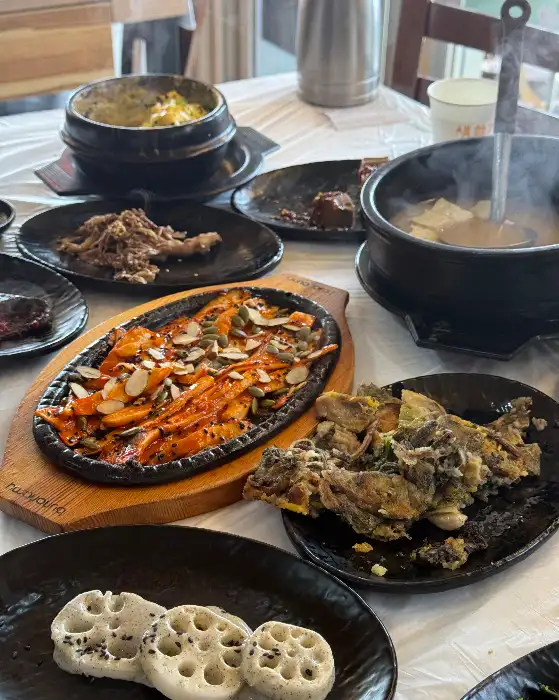 화려하고 다채로운 나물 반찬과 메인 요리가 먹음직스럽게 차려진 산나물밥상 테이블