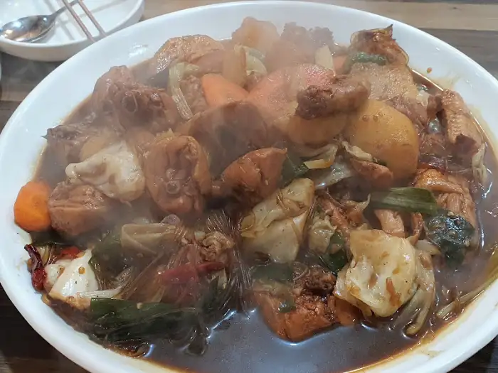 김이 모락모락 피어나는 안동양반찜닭의 찜닭, 푸짐한 닭고기와 채소가 가득하다