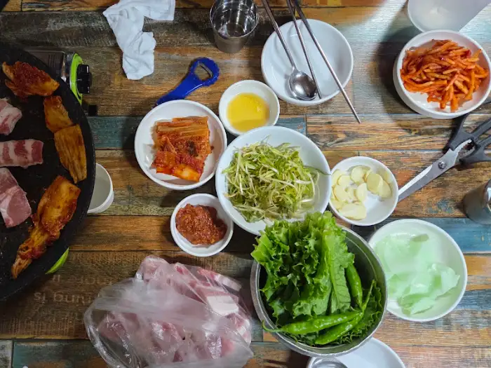 식탁 위 푸짐하게 차려진 삼겹살과 반찬들