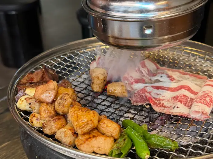 숯불 위에서 곱창과 함께 구워지는 우삼겹과 청양고추