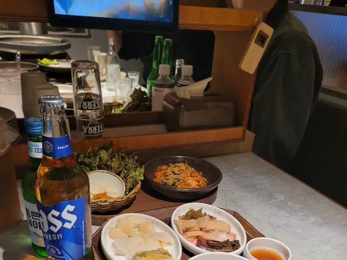 테이블 위에 놓인 맥주와 밑반찬, 국물 요리