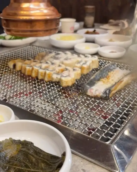 테이블 위에서 숯불에 구워지고 있는 장어와 밑반찬들