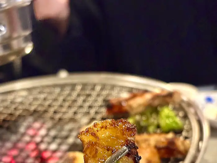 집게로 집어 올린 먹음직스러운 숯불 곱창구이 한 점