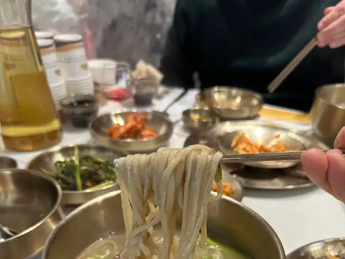 국수 가락을 집게로 들어 올리는 모습