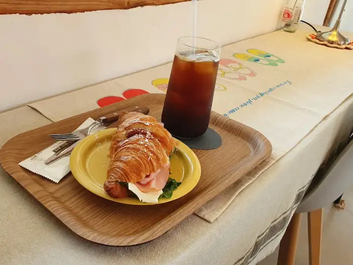 크루아상 샌드위치와 아이스 아메리카노가 담긴 우드 트레이