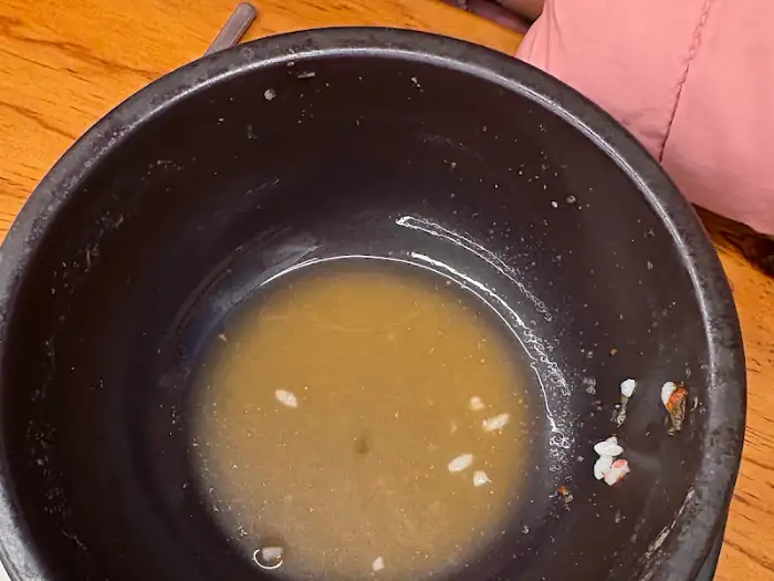 식사를 마친 후 남은 국물이 담긴 뚝배기, 빈 그릇으로 만족스러운 식사를 짐작케 함
