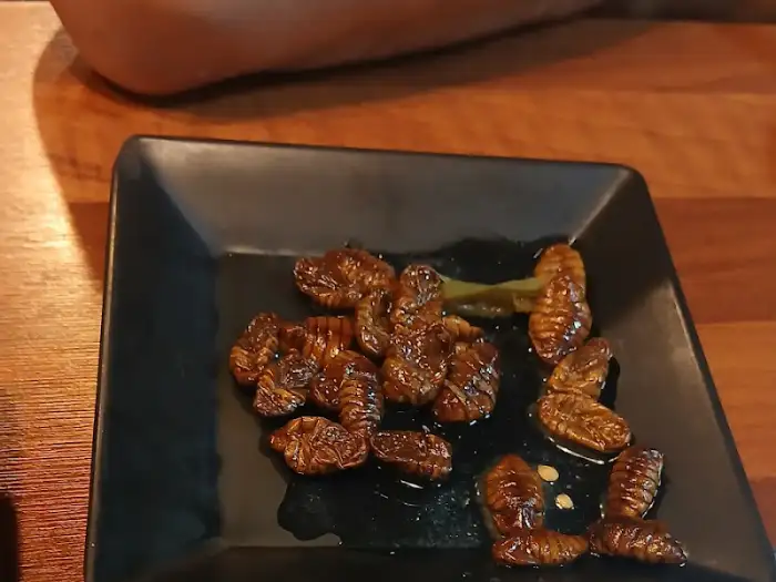 검은 접시에 담긴 번데기 요리