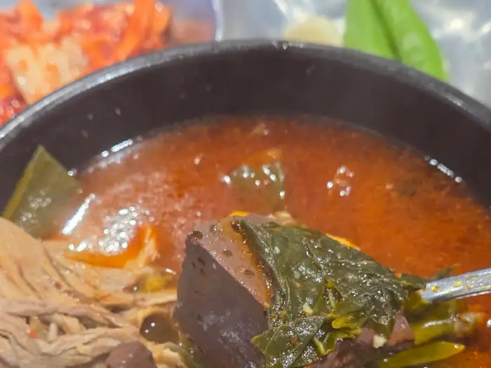 김치와 함께 보이는 해장국의 국물과 건더기 일부