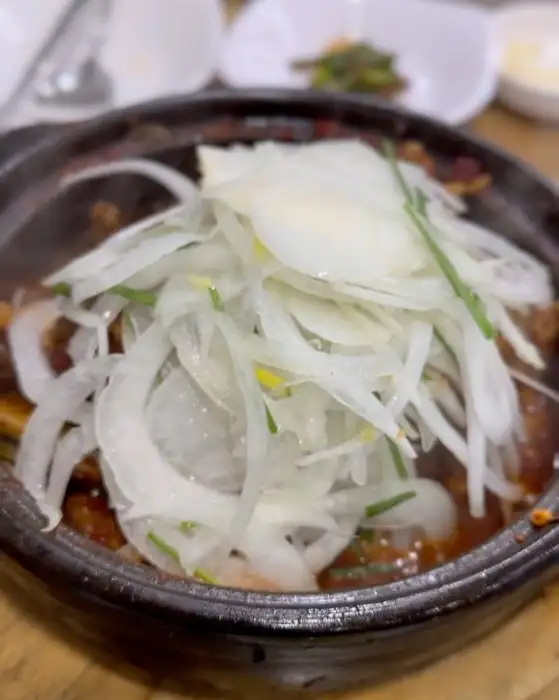 뜨겁게 끓고 있는 매콤달콤한 갈비찜 위로 얇게 썬 양파와 파가 듬뿍 올라가 있는 모습