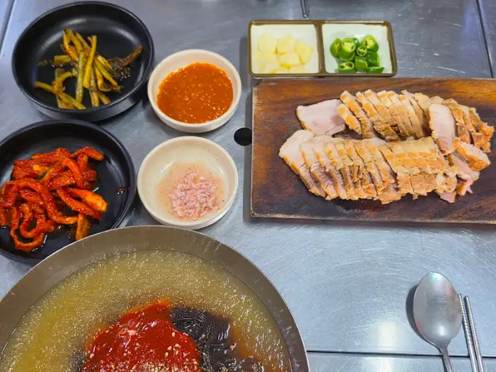 푸짐하게 차려진 보쌈, 냉면, 그리고 다양한 밑반찬 한 상 차림