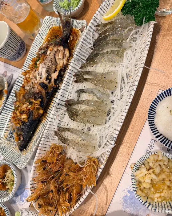 먹음직스럽게 구워진 생선구이와 신선한 새우가 함께 담겨 있습니다.