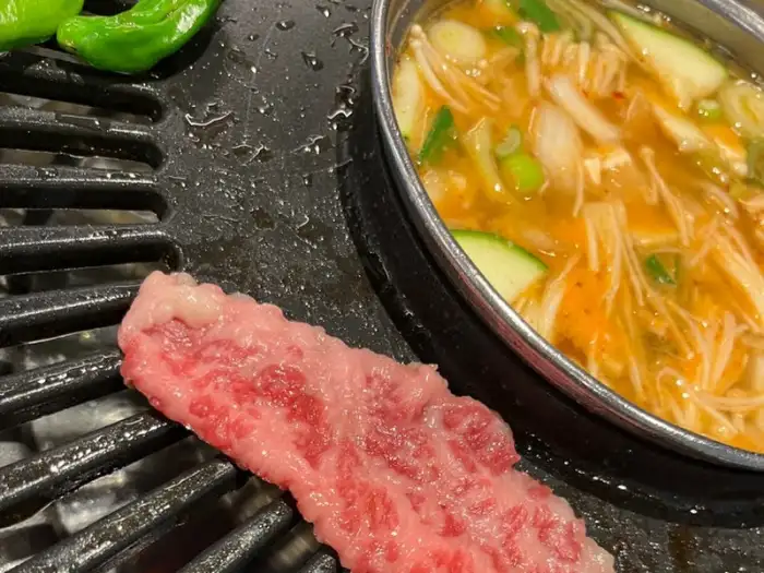 숯불 위에 구워지고 있는 신선한 육류와 찌개