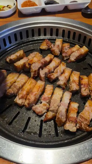 잘 구워진 오겹살 조각들이 불판 위에 가득 채워져 있습니다.
