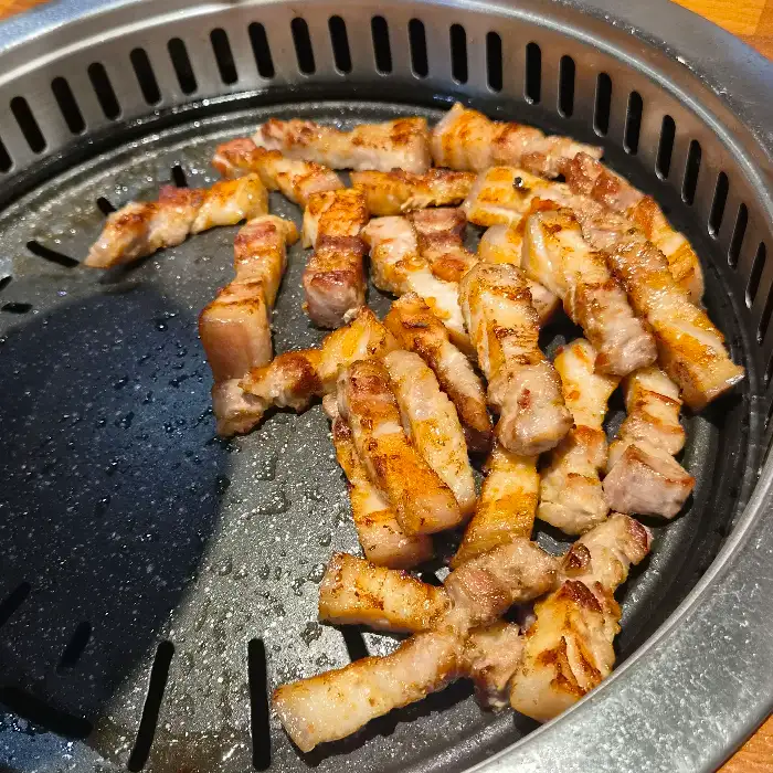 불판 위에서 노릇하게 구워지고 있는 오겹살 조각들