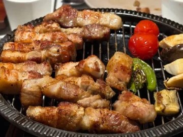 잘 구워진 삼겹살과 방울토마토, 아스파라거스가 함께 나온 고기 메뉴
