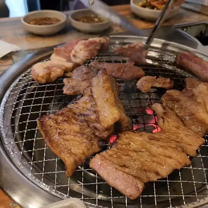 숯불 위에서 노릇하게 구워지고 있는 돼지갈비 여러 점
