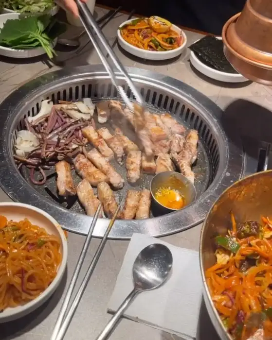테이블 위에서 고기를 굽고 있는 모습과 함께 나오는 다양한 밑반찬