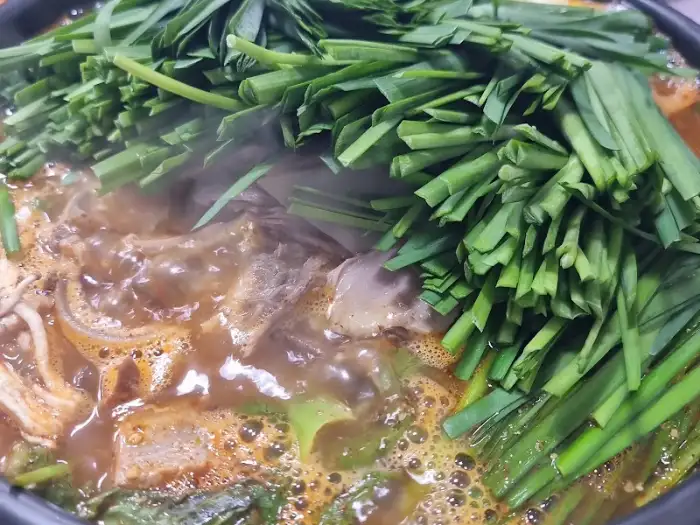 과천식당 보신탕 뚝배기에 끓고 있는 모습, 국물과 고기, 채소가 어우러짐