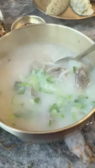 그릇에 담긴 설렁탕에 숟가락을 넣어 국물을 뜨는 모습