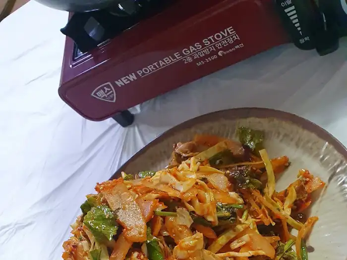 가자미회무침 위에 놓인 휴대용 가스레인지와 냄비