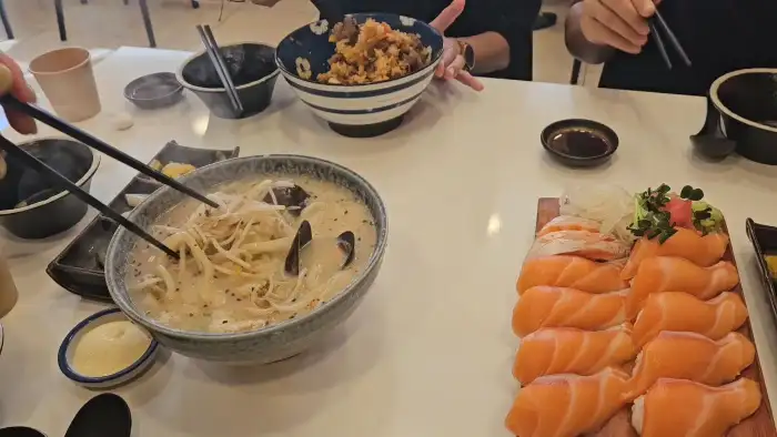 식사 중인 테이블의 모습, 연어초밥과 우동이 보인다