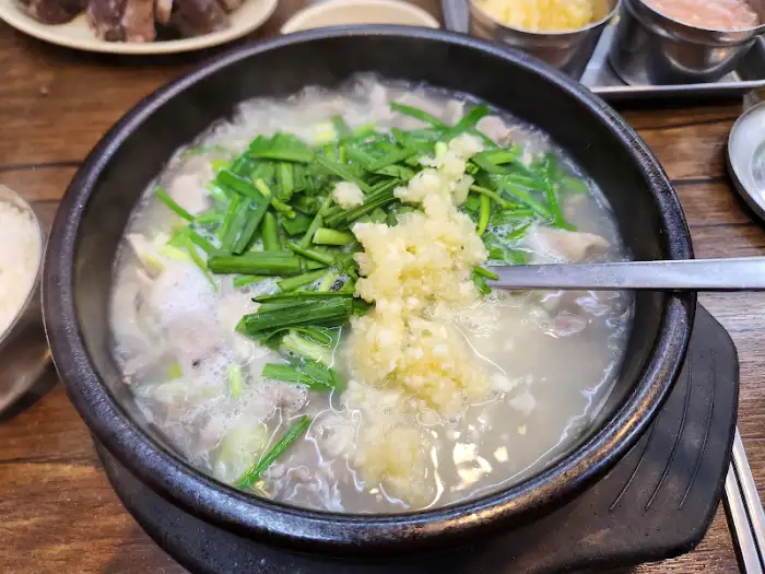 화천 식당의 국밥에 다진 마늘과 파를 듬뿍 올린 모습, 풍성한 고명으로 맛을 더한 모습