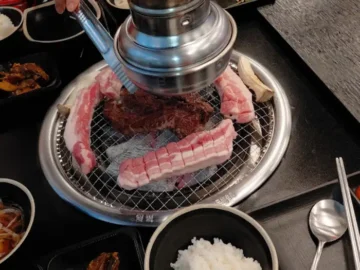 팔삼정육식당 오학점의 두툼한 생삼겹살이 숯불 위에서 구워지고 있는 모습