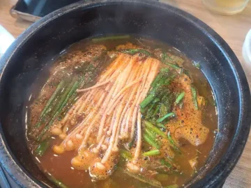 오리탕에 팽이버섯과 파가 푸짐하게 담겨 있는 모습